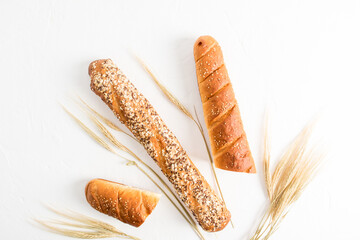 two types of baguette with different seeds on a white background with ears of wheat. top view. flat...