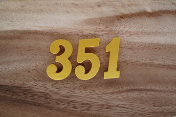 Golden Arabic numerals on a real brown and white wooden floor number 351