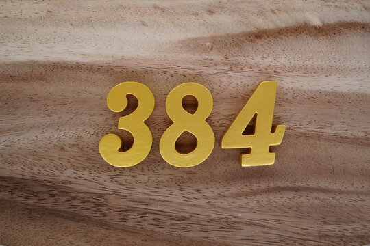 Golden Arabic numerals on a real brown and white wooden floor number 384