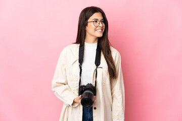 Young photographer Brazilian girl isolated on pink background looking side