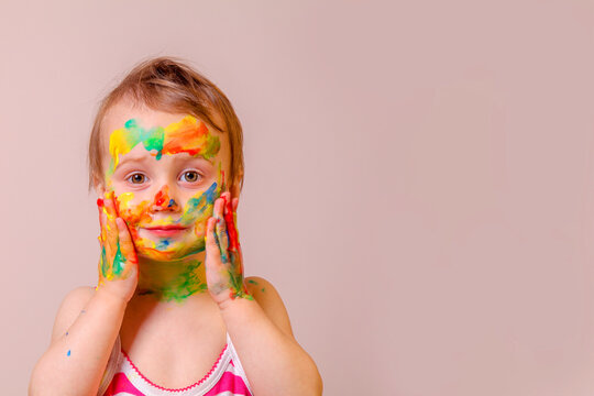 Humorous image of childrens makeup. Beauty, fashion, happy childhood concept. Portrait of beautiful young child girl with painted face and hands. Horizontal image.