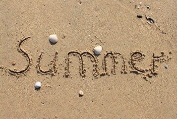 Fototapeta na wymiar on the beach is carved with letters in the smooth sand the writing SUMMER