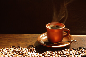 A brown cup of coffee on a saucer from which steam flows. 