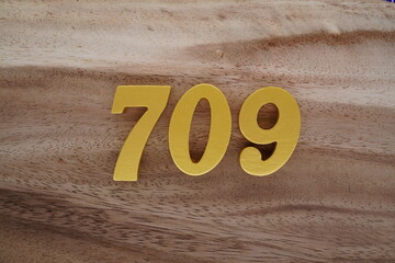 Golden Arabic numerals on a real brown and white wooden floor number 709