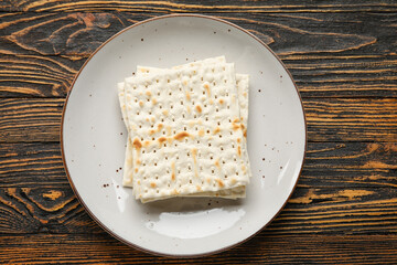 Plate with Jewish flatbread for Passover on wooden background