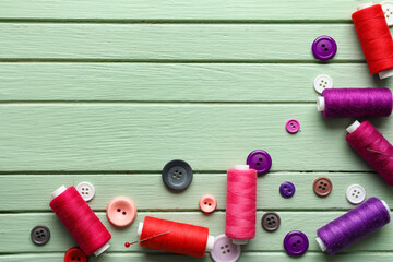 Sewing threads with buttons on color wooden background