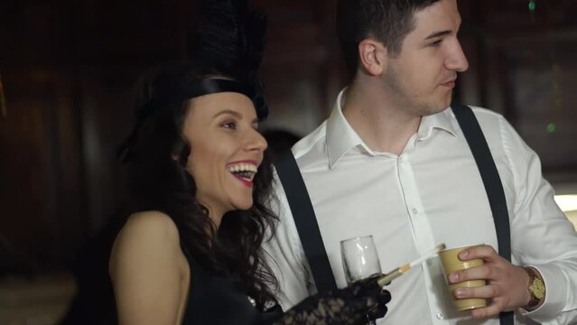 Beautiful woman and a man, glamourous couple dressed in Roaring twenties costumes drinking champagne and dancing on a themed Gatsby party Vintage, retro party, 20s fashion concept
