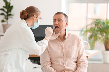 Obraz premium Doctor examining man with sore throat in clinic