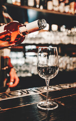 bartender pouring red wine into a glass in cafe or bar on the bar counter