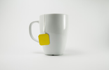 White cup of hot tea with a yellow tag bag inside.