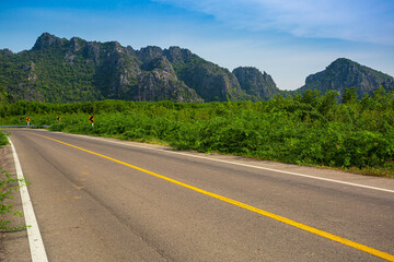 Naklejka premium Rural asphalt road among the fields in summer season 