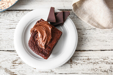 Plate with pieces of delicious chocolate brownie on white wooden background