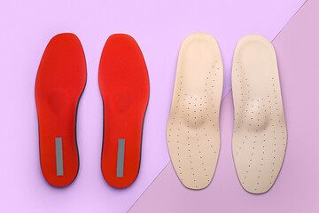 Two pairs of orthopedic insoles on lilac background