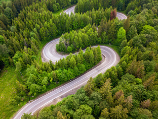 Winding road from high mountain pass, in summer time. Aerial view by drone . Romania