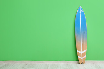Modern surfboard near green wall in room