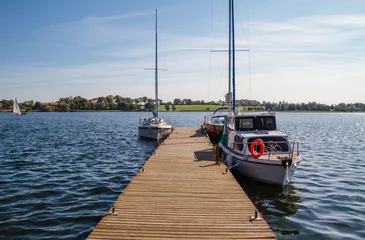 Foto op Plexiglas Peaceful blue lake with small wooden pier and private sailing boats or yachts. © Longfin Media