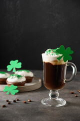 Irish coffee in glass cup and cupcakes for St Patricks Day on green background. Vertical format....