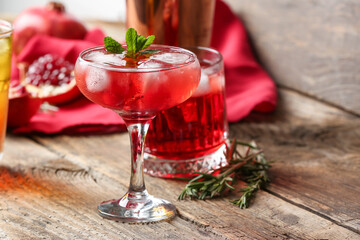Glasses of tasty pomegranate cocktail on wooden background