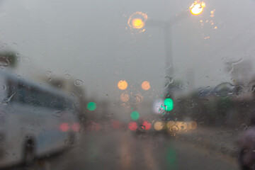 Blurry car silhouette seen through water drops on the car windshield