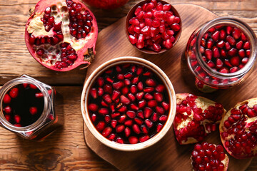 Jars and bowl of pomegranate molasses with fresh fruits on wooden background