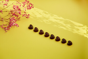 Spring festive vintage background with shadows, chocolate hearts and gypsophila flowers. Women's Day present and greeting concept. Copy space