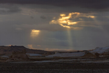 Rays through the clouds and wind eroded rock formations in the evening, Egyptian White Desert....
