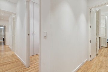 Distributor corridor of a residential house with wooden floors, white wood carpentry in doors and windows and white painted walls