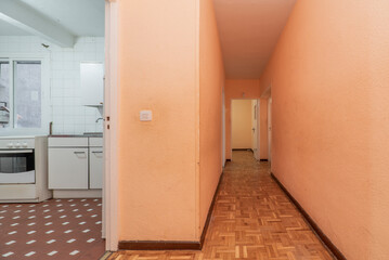 Fototapeta na wymiar Hallway of a residential apartment building with oak parquet floors and access to a kitchen with clay terrazzo floors