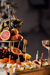 Fresh fruits in plate on wooden table. Variety of cut fruits. Assorted fruits. Kiwis,grapes,orange, bananas,apples,pears