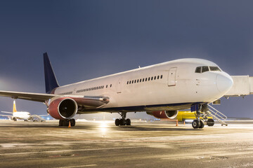 Fototapeta na wymiar Wide body passenger aircraft at the airport apron at winter night