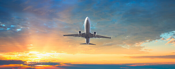 Fototapeta premium Airplane flying over tropical sea at sunset