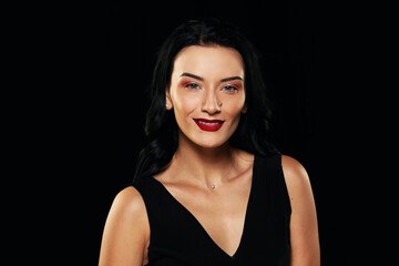 Fototapeta na wymiar Portrait of a girl on a black background. Studio shooting. Brunette with bright red lips.