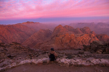 Woman tourist waiting for sunrise on the summit of the Holy Mount Moses (Mount Sinai, Mount Horeb or Jabal Mousa), Egypt, North Africa. Low exposure