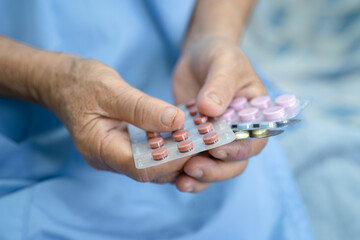 Obraz na płótnie Canvas Asian senior or elderly old lady woman patient holding antibiotics capsule pills in blister packaging for treatment infection patient in hospital, Pharmacy drugstore concept. 