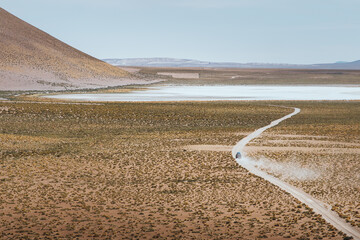 Car traversing a dirt road through an arid landscape with mountains in the background © Dani Palazón
