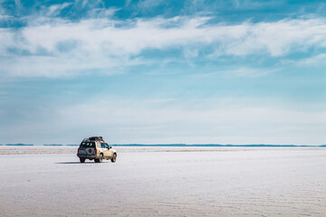 Car with luggage on the roof crossing a salt desert - Uyuni Salt Flat
