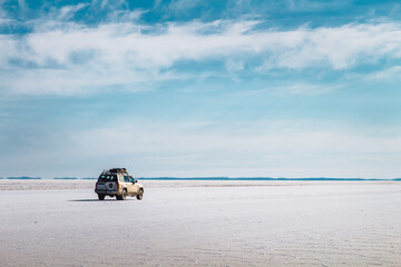 Car with luggage on the roof crossing a salt desert - Uyuni Salt Flat © Dani Palazón