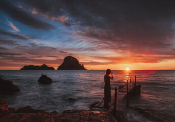 Red sunset in Cala d,Hort with girl on bridge with  Es Vedra Island  , Ibiza .