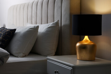 Stylish lamp on bedside table indoors. Bedroom interior element