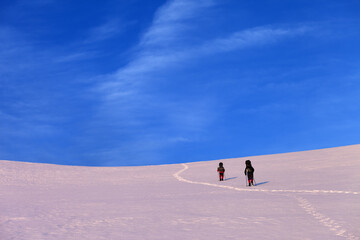 Fototapeta na wymiar Two hikers on sunrise snowy plateau
