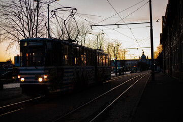 Naklejka na ściany i meble Silhouette of tram leaving Lviv train station during the sunset