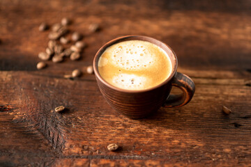 Cup with coffee and coffee beans on a wooden background.