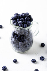 Blueberries in a glass jug on a white background. The benefits of berries, vegetarianism concept.