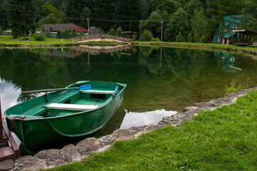 Boat on the shores of a mountain lake, calm water and green forest