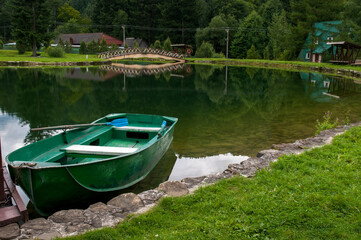Obraz premium Boat on the shores of a mountain lake, calm water and green forest