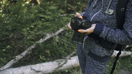 Naklejka premium Traveler photographing scenic view in forest. One caucasian woman shooting close up look. Girl take photo video on dslr mirrorless camera. Professional photographer travel with backpack. Outdoor.