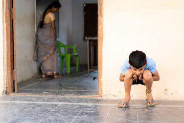 Kid sitting outiside the calss by holding ears as punishment - concept of childhood mischief and...