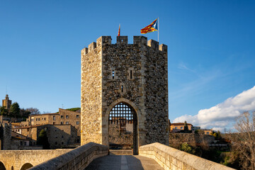 Besalu historic medieval city with Catalonia flags on the stone bridge tower crossing El Fluvia...