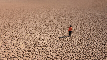 Silhouette of a man on a sandy cracked empty not fertile land during a drought. The concept of...
