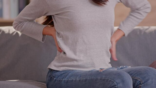 A woman is trying to exercise by twist her upper body, but she has a bit ache and pain on her back. She needs massage and cracking her back to release her tight. She's pushing on the back bone.